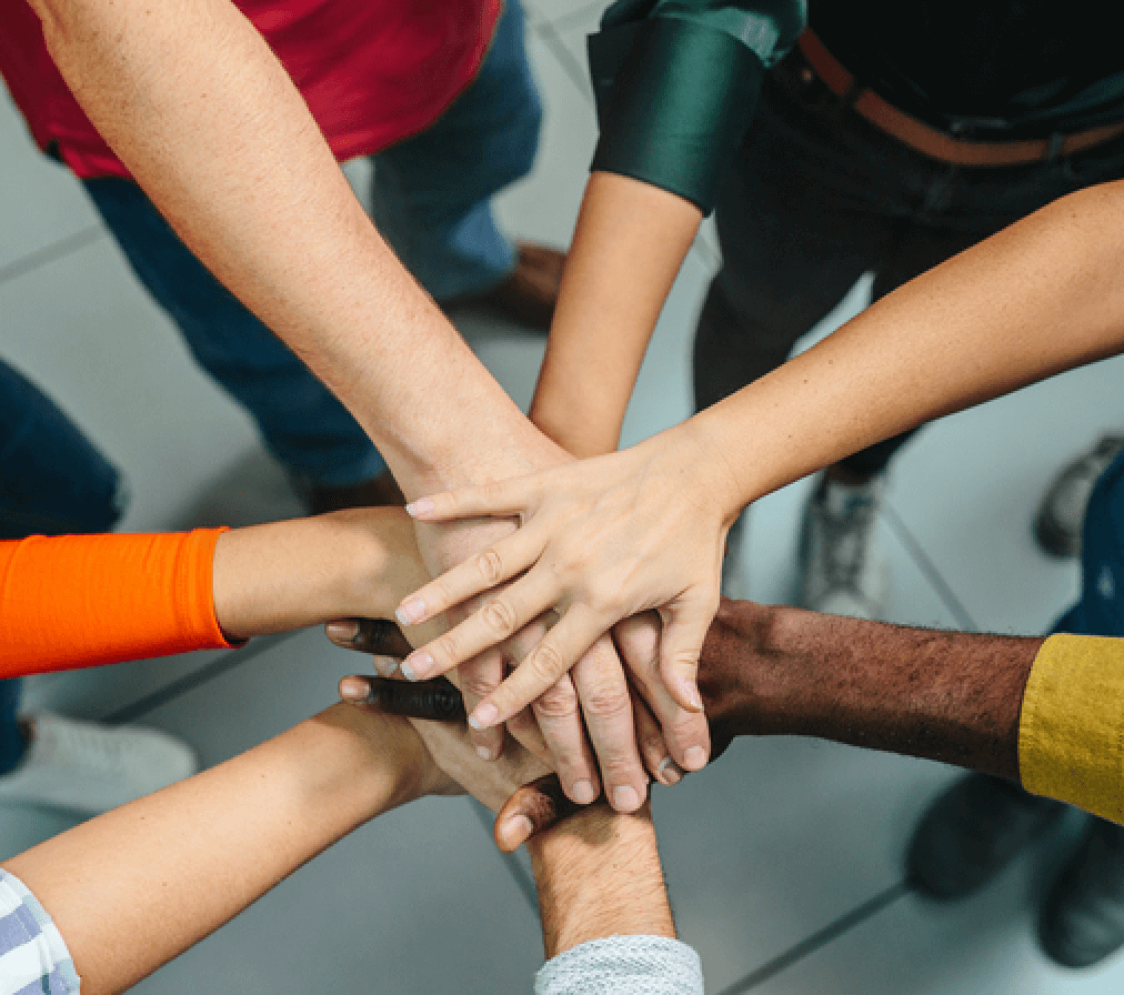 Several hands placed on top of each other, in celebration of an achievement