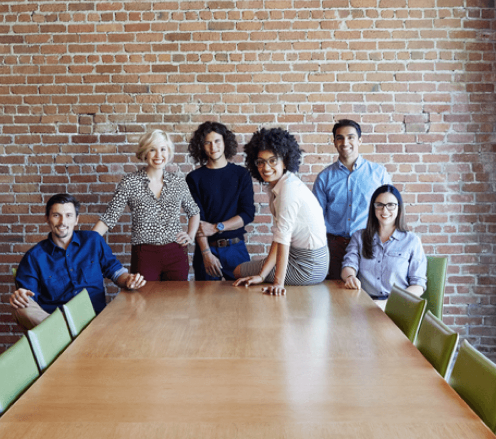 Several people in a meeting room smiling at the camera