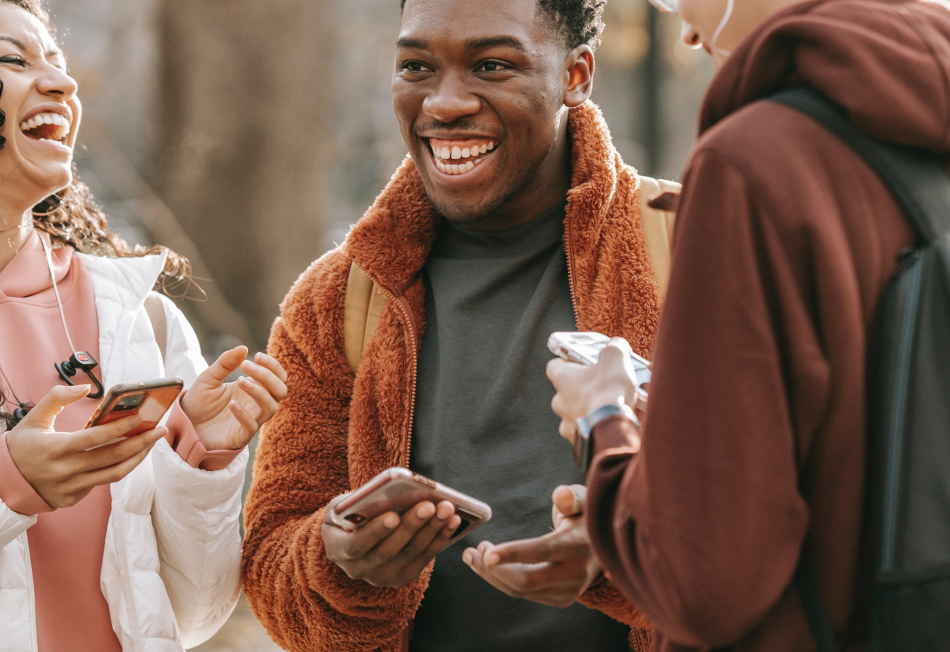 Several people laughing while holding their phones.